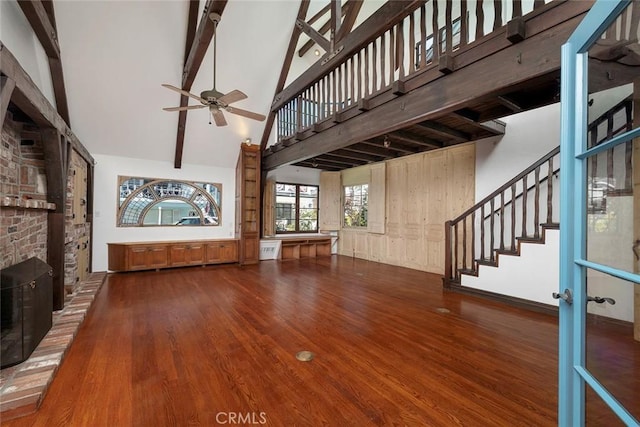 unfurnished living room with hardwood / wood-style floors, high vaulted ceiling, ceiling fan, and beam ceiling