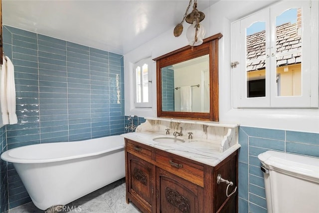 bathroom featuring a washtub, vanity, and tile walls