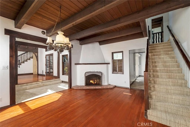 unfurnished living room featuring a fireplace, beamed ceiling, wood ceiling, and hardwood / wood-style flooring