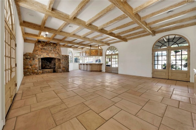 unfurnished living room with french doors, a fireplace, plenty of natural light, and beam ceiling