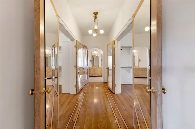 corridor featuring light hardwood / wood-style flooring and an inviting chandelier