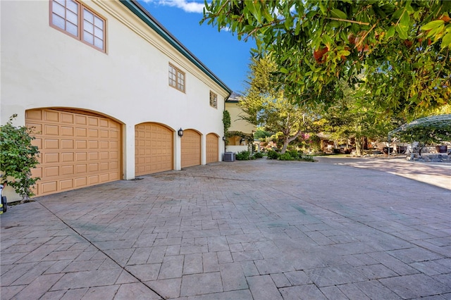 view of side of property featuring central air condition unit and a garage