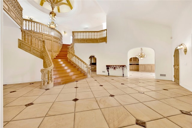 stairway with a notable chandelier, a towering ceiling, and tile patterned flooring