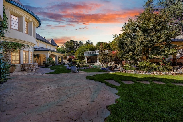 yard at dusk featuring a patio area