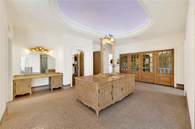 bedroom with a raised ceiling, light carpet, and access to exterior