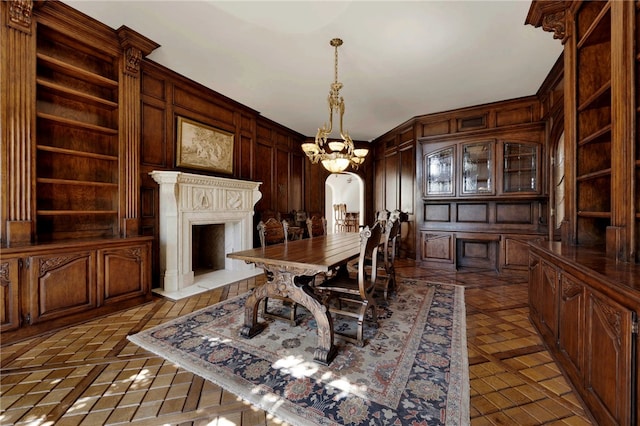 dining area with an inviting chandelier, wooden walls, and built in shelves