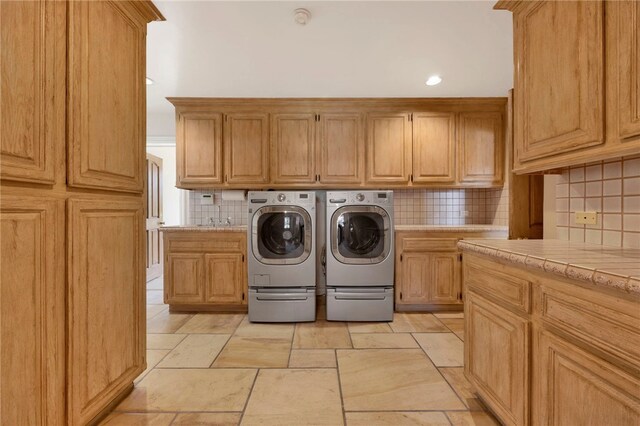 clothes washing area featuring cabinets, washer and dryer, and sink