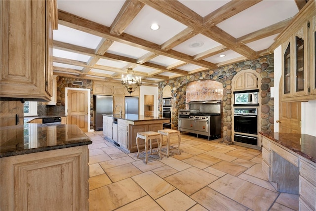 kitchen with a kitchen island with sink, a breakfast bar area, a notable chandelier, beam ceiling, and stainless steel appliances