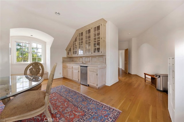 kitchen featuring dishwasher, sink, vaulted ceiling, light hardwood / wood-style flooring, and cream cabinets