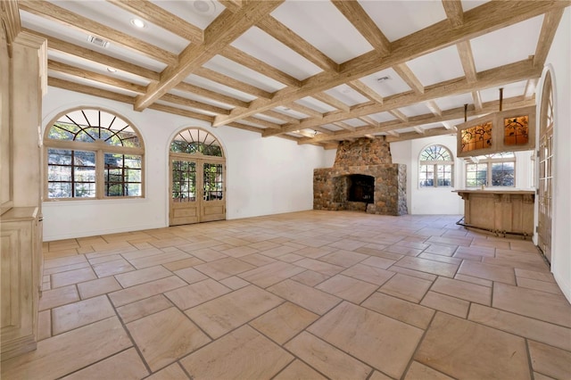 unfurnished living room featuring beamed ceiling, coffered ceiling, and a stone fireplace