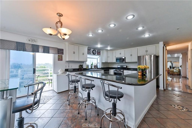 kitchen with hanging light fixtures, appliances with stainless steel finishes, white cabinetry, and a kitchen island