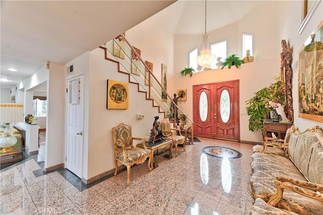 entrance foyer with a towering ceiling, plenty of natural light, and a chandelier