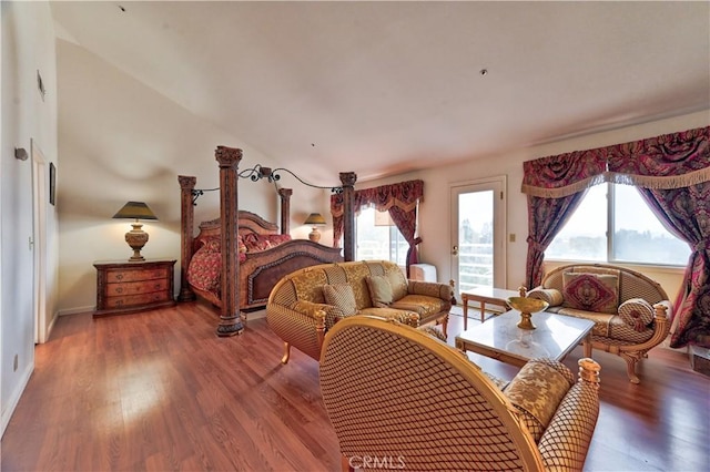 bedroom with access to exterior, lofted ceiling, and hardwood / wood-style floors