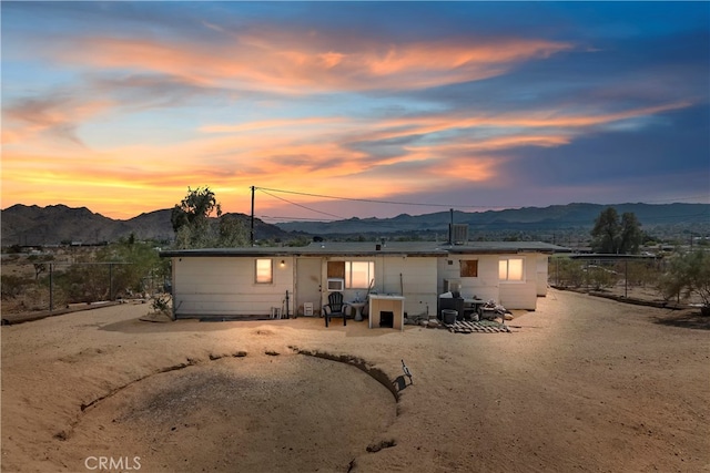 back house at dusk featuring a mountain view and a patio