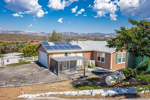 view of front facade featuring a mountain view, a garage, solar panels, and a patio area