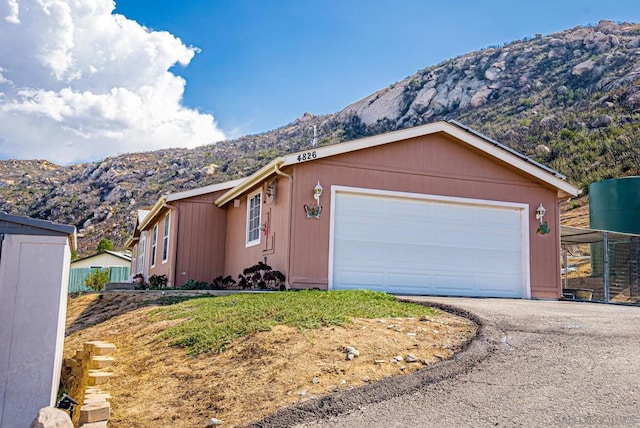 ranch-style home featuring a mountain view, a garage, and a shed