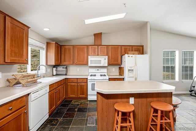 kitchen with sink, white appliances, a kitchen island, a breakfast bar area, and vaulted ceiling