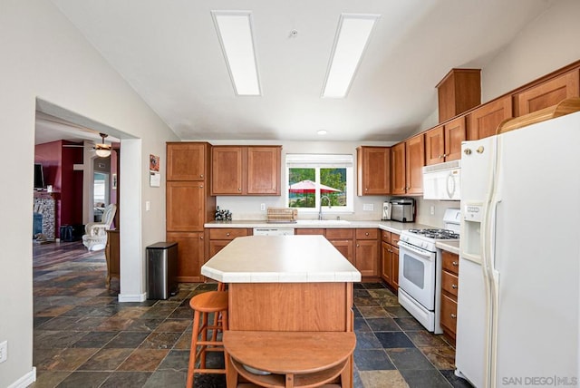 kitchen featuring a breakfast bar area, sink, lofted ceiling, a kitchen island, and white appliances