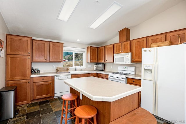 kitchen featuring sink, white appliances, a center island, a breakfast bar area, and vaulted ceiling