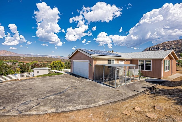 view of front of property with a patio, a mountain view, solar panels, and a garage