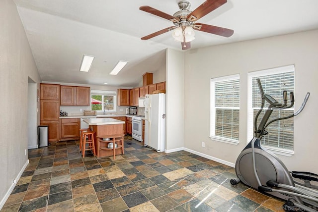 kitchen featuring lofted ceiling, a kitchen bar, a kitchen island, appliances with stainless steel finishes, and ceiling fan