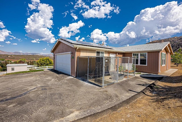 ranch-style house featuring solar panels, a mountain view, and a patio area