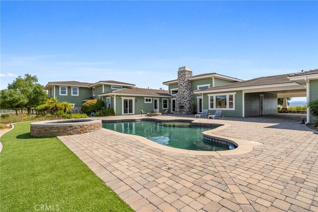 view of swimming pool featuring a patio area, an in ground hot tub, and a lawn