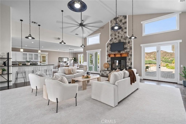 living area featuring high vaulted ceiling, a healthy amount of sunlight, wood finished floors, and a fireplace