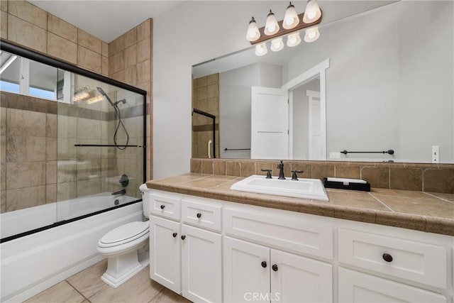 bathroom featuring vanity, tile patterned floors, toilet, and bath / shower combo with glass door