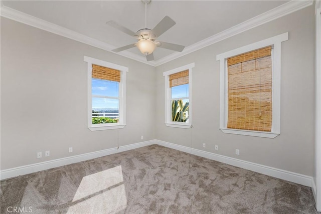 carpeted spare room with baseboards, a ceiling fan, and crown molding