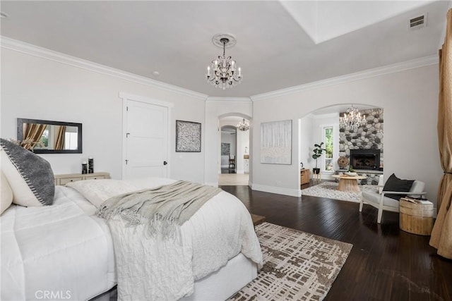 bedroom featuring visible vents, ornamental molding, hardwood / wood-style floors, arched walkways, and a chandelier