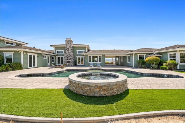 view of swimming pool featuring a patio area, a yard, and an in ground hot tub