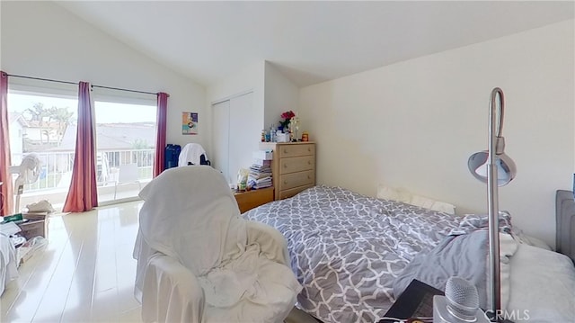 bedroom with access to outside, vaulted ceiling, a closet, and light hardwood / wood-style floors