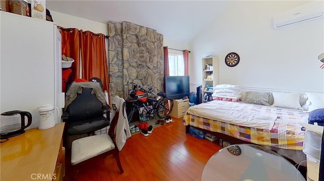 bedroom featuring an AC wall unit, lofted ceiling, and hardwood / wood-style floors