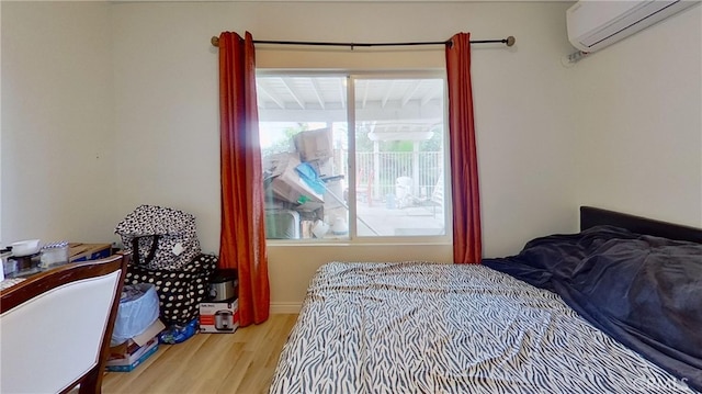 bedroom with light wood-type flooring and a wall unit AC