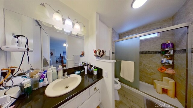 bathroom with tile patterned flooring, an enclosed shower, vanity, and toilet