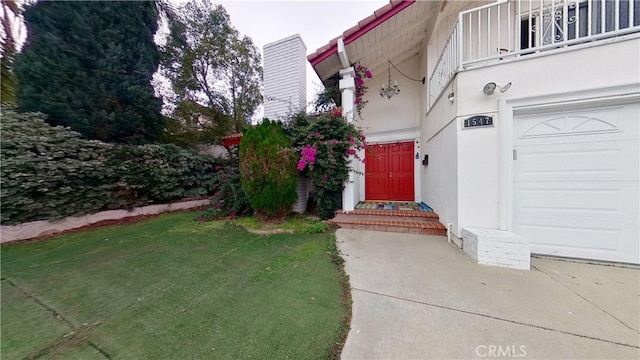 entrance to property with a lawn, a balcony, and a garage