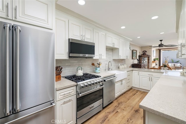 kitchen featuring premium appliances, white cabinets, light hardwood / wood-style flooring, and sink