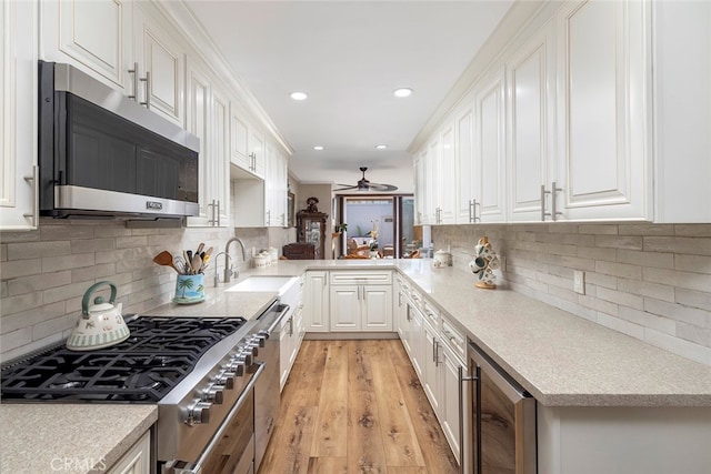 kitchen with wine cooler, sink, white cabinetry, light hardwood / wood-style flooring, and stainless steel appliances