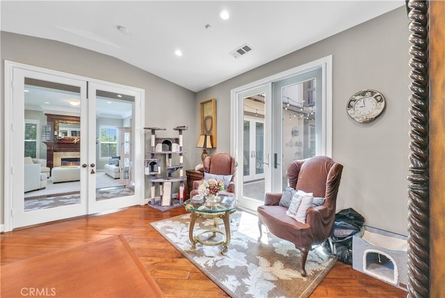 living area with lofted ceiling, wood-type flooring, and french doors