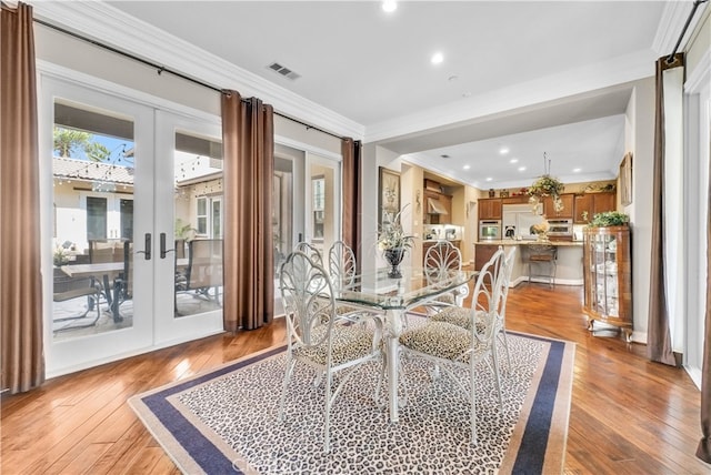 dining room featuring french doors, light hardwood / wood-style floors, and crown molding