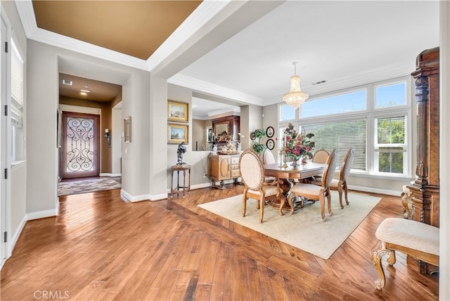 dining area featuring ornamental molding, an inviting chandelier, and light hardwood / wood-style floors