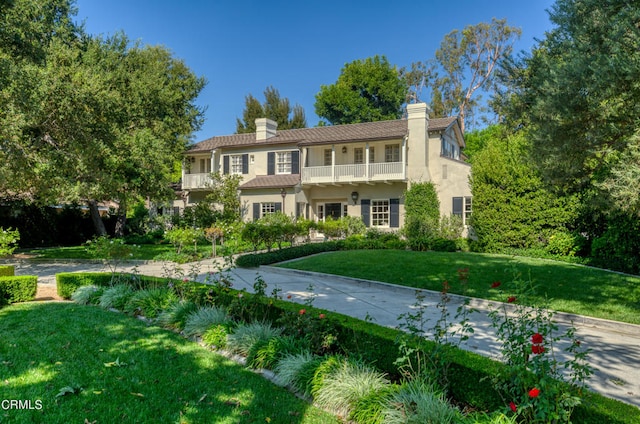 view of front of house featuring a front lawn and a balcony