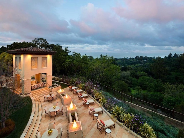 patio terrace at dusk with an outdoor fireplace and a fire pit