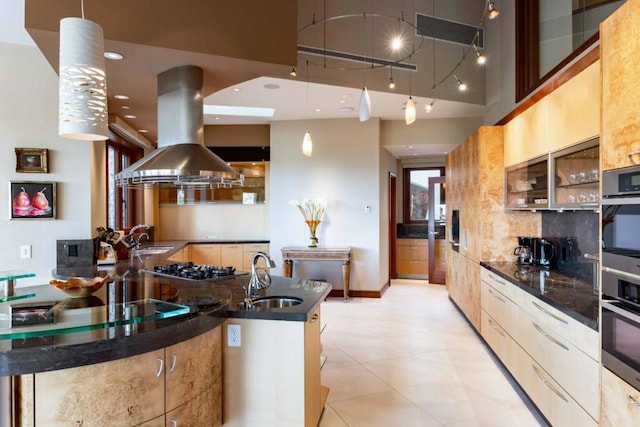 kitchen with sink, hanging light fixtures, island exhaust hood, and a towering ceiling