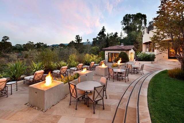 patio terrace at dusk with a fire pit and an outdoor structure