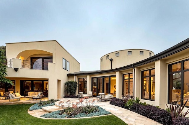 rear view of house with a balcony, a yard, and a patio area