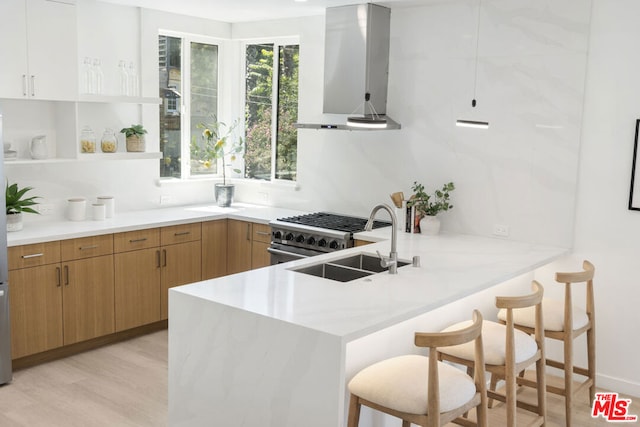 kitchen with kitchen peninsula, sink, ventilation hood, a kitchen bar, and light wood-type flooring