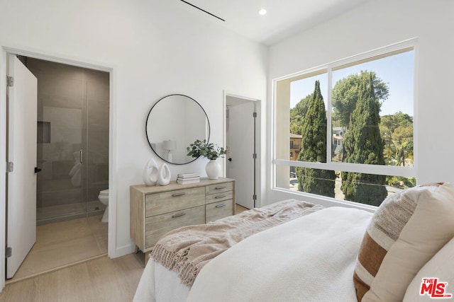 bedroom with ensuite bathroom and light wood-type flooring