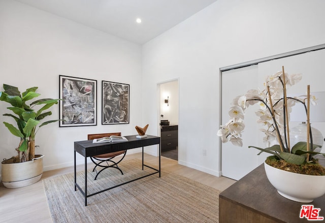 office area with a high ceiling and light hardwood / wood-style floors